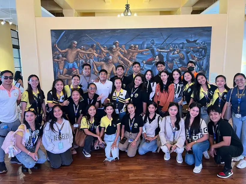 A student delegation posing in front of a large painted mural