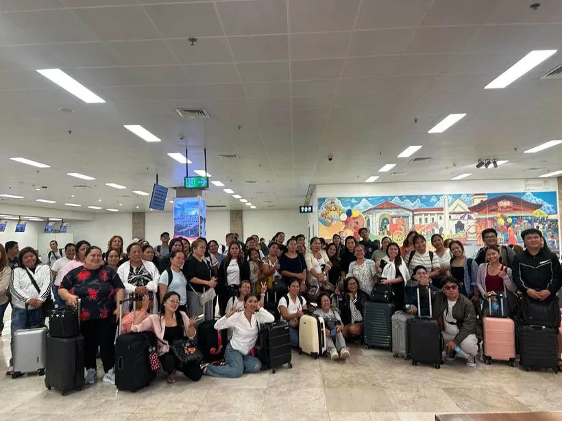 A large tour group with suitcases in an airport hall