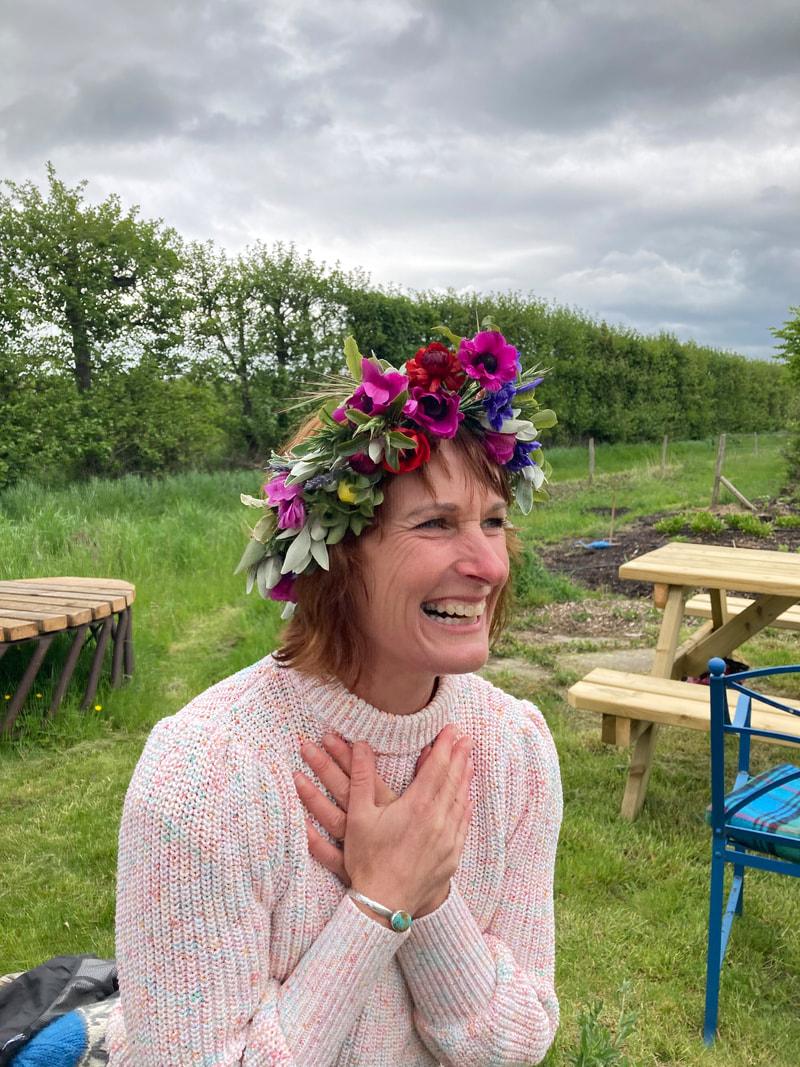 Caroline laughing in a garden, wearing a flower crown