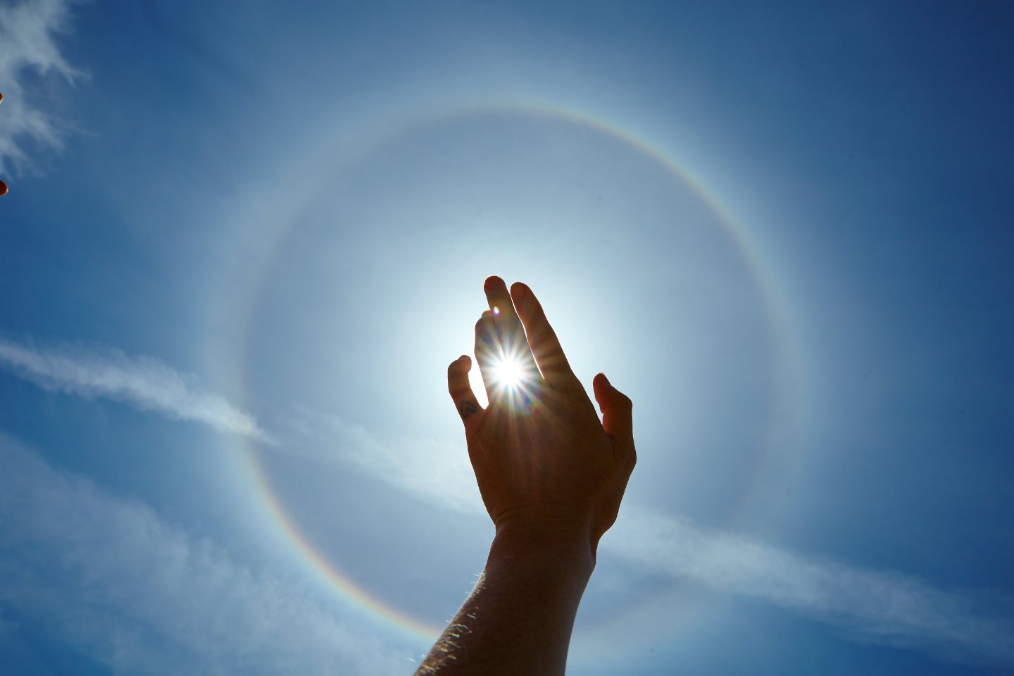 Mână ridicată spre soare, cu un halo de lumină